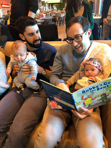 Two fathers reading books to their babies