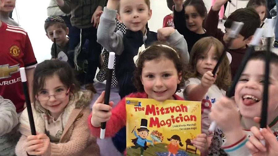 Children posing with magic wands and the book Mitzvah Magician