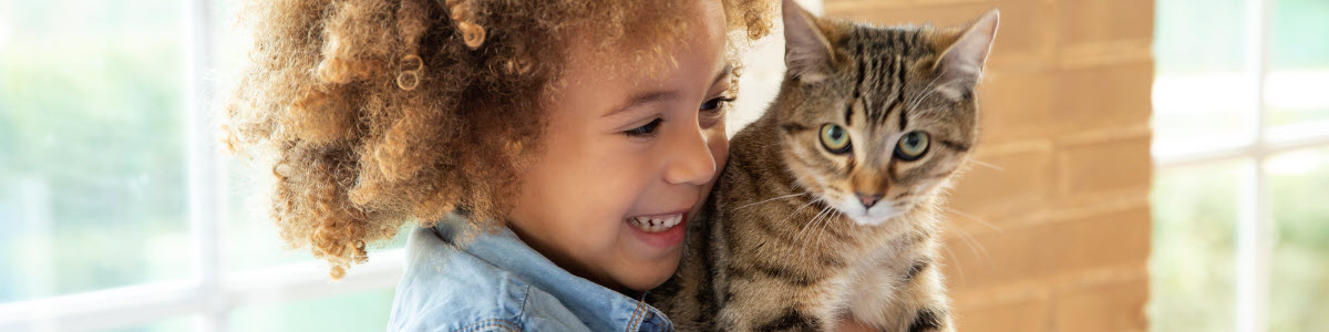 A small child gently holds a kitten