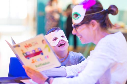 A parent reading to a child with masks on