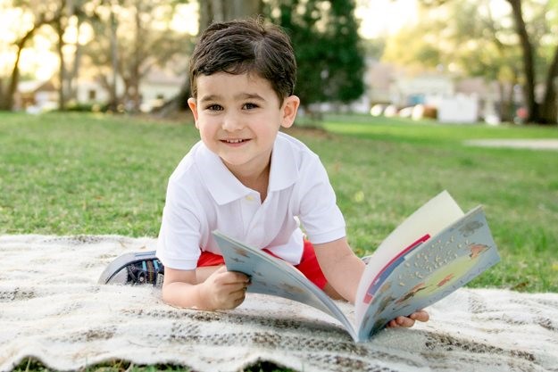 Boy reading on picnic blanket