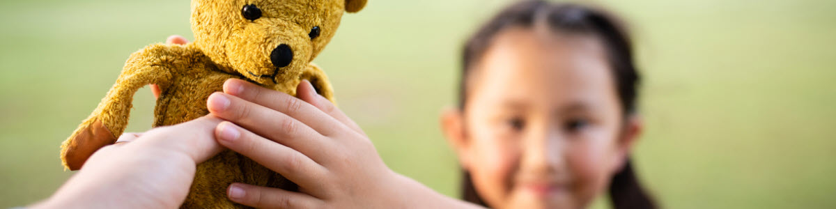 An adult hands a teddy bear back to a child