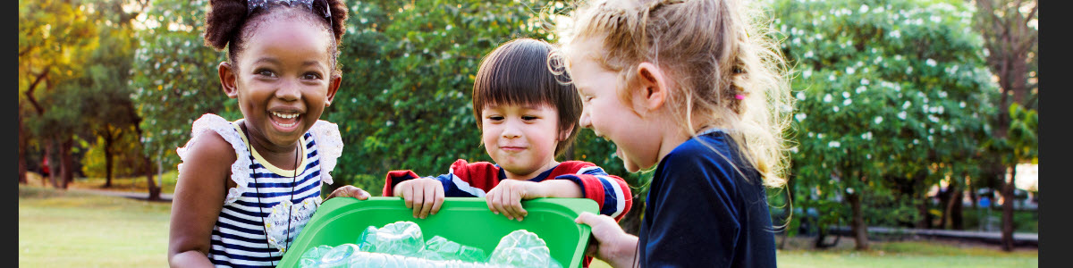 Several children hold a recycling bin together